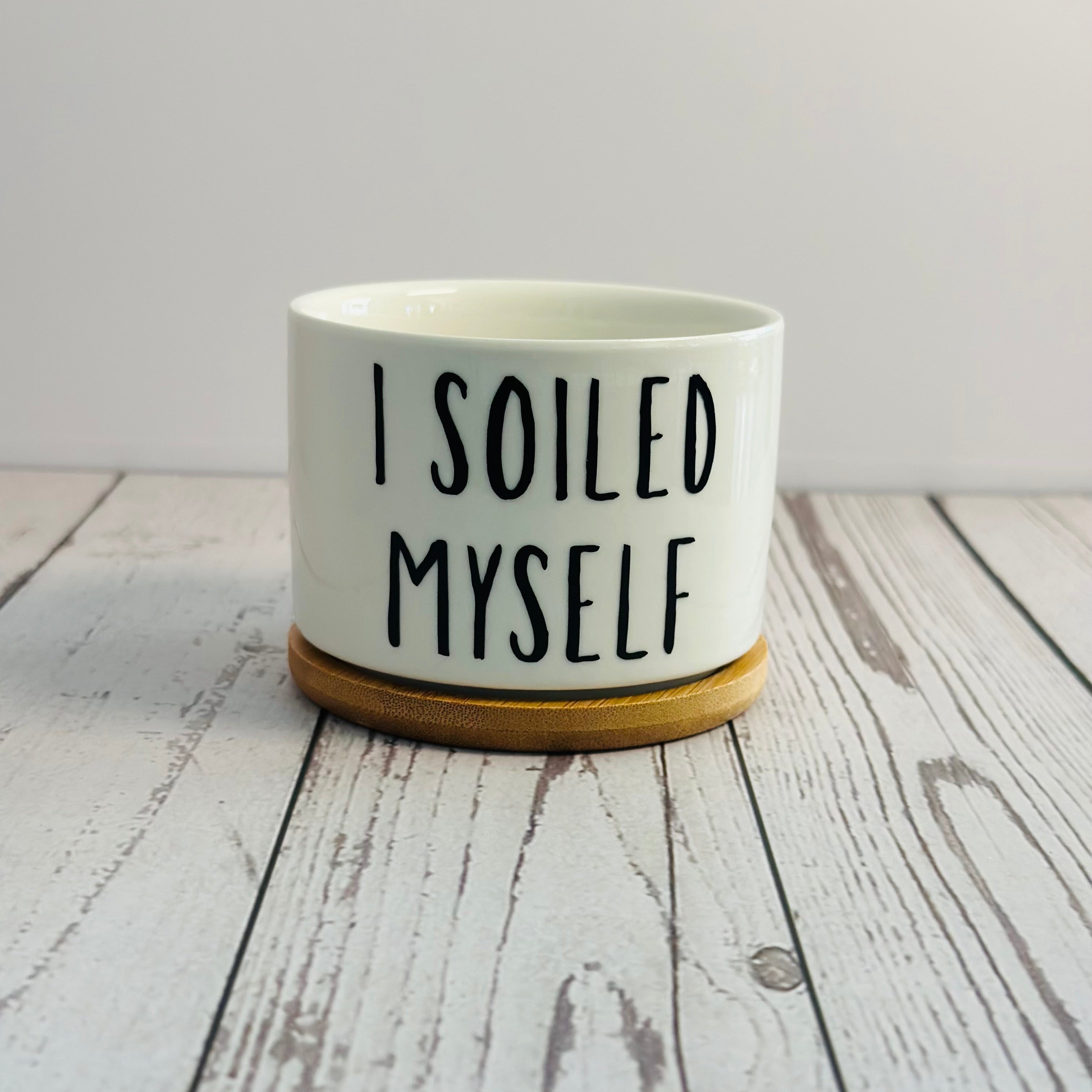 White mug with 'I SOILED MYSELF' text on a wooden surface