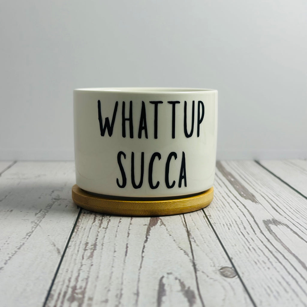 White container with 'WHAT UP SUCCA' text on a wooden surface