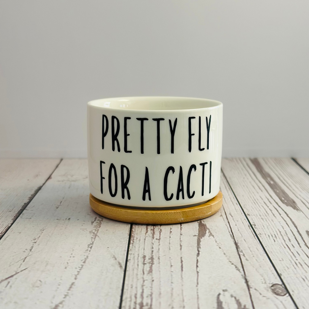 White ceramic pot with black text on a wooden surface